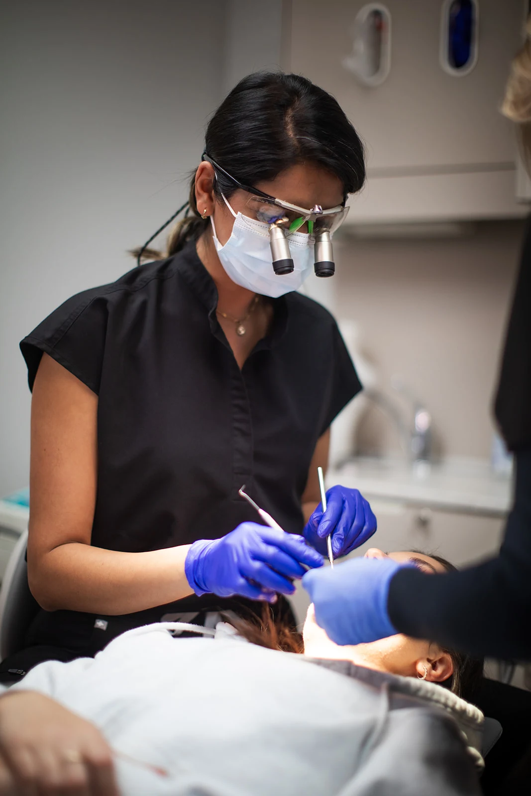 A clinician wearing magnifying glasses while treating a patient