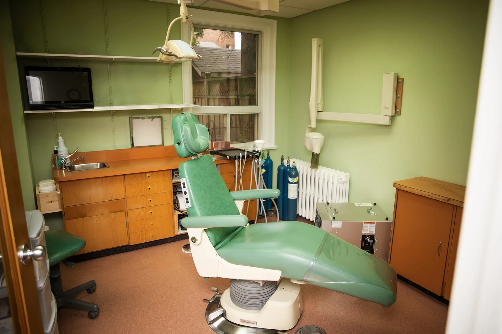 A dental chair and equipment in a green treatment room
