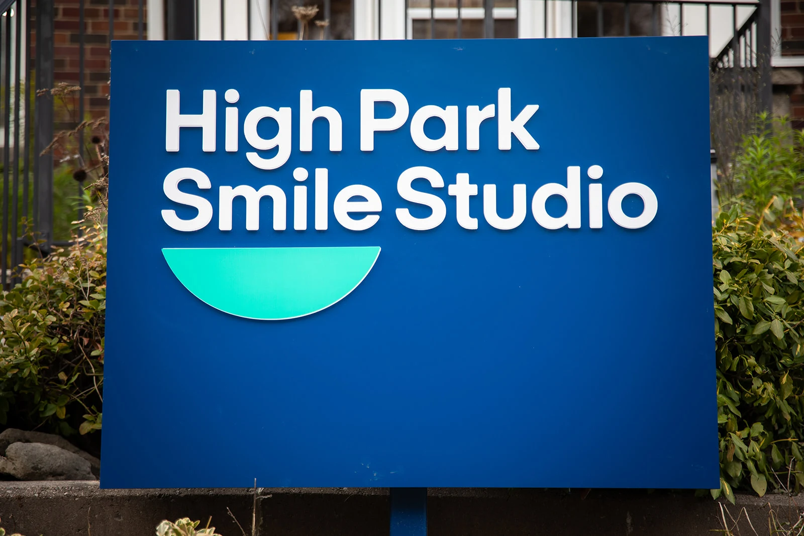 The navy and teal High Park Smile Studio sign outside the office